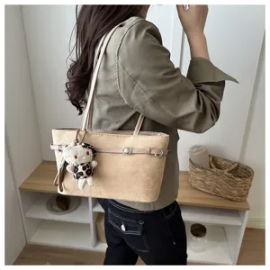 Borsa beige effetto scamosciato indossata a spalla, con fibbie e ciondolo orsetto leopardato