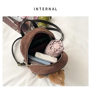 Top-down detail of the open brown suede-texture bag, showing black straps, zipper and interior