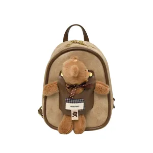 Mini backpack in tan suede-look fabric with dark brown trim and a plush teddy bear charm
