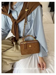 Imagen de una modelo con minibolso marrón acolchado, asa dorada y correa de cadena al hombro