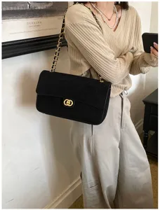 Black quilted suede-look bag worn on the shoulder, with a gold chain strap and double-ring clasp
