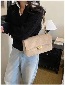 Beige suede-look flap bag with quilted diamond stitching and gold chain, worn over the shoulder