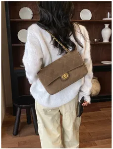 A model wears a brown quilted bag with a gold chain strap and clasp, shown from behind