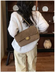 Back view of a model wearing a brown quilted flap shoulder bag with a gold chain strap