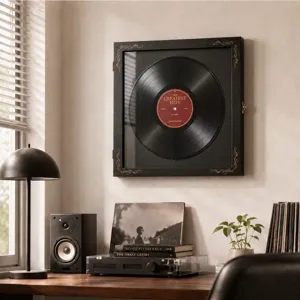 Black vinyl record in an ornate wall frame, displayed above a turntable in a warm living room