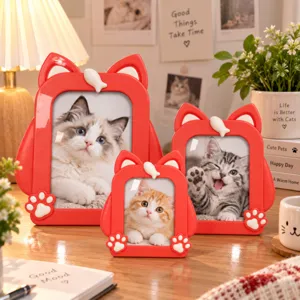 Three red cat-shaped photo frames in different sizes, with white fish and paw details on a table