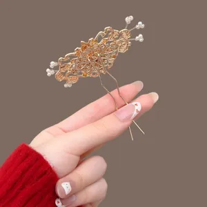 Traditional-style gold-tone openwork hair fork with pearl flower accents, shown held in hand