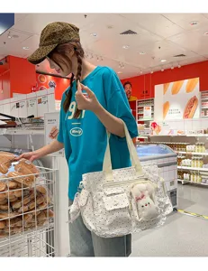 Sac blanc à pois, bordure en dentelle et ourson en peluche, porté à l'épaule dans un magasin