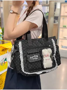 Sac noir à pois porté à l’épaule, bordé de dentelle blanche, avec poches zippées et fenêtre claire