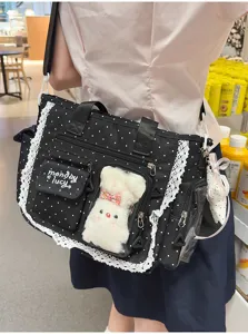 Sac noir à pois vu de dos, avec bordure en dentelle, poches frontales et breloque en peluche