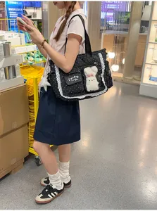 Vue en situation d’un sac noir à pois, bordé de dentelle, avec un ours en peluche dans un magasin