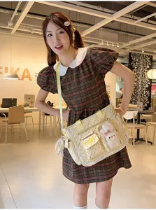 Le modèle porte un sac bandoulière jaune à pois, bordure en dentelle, fenêtre transparente et breloques