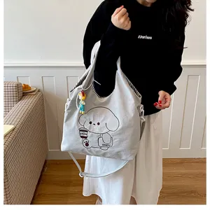 Sac en toile gris clair porté par un modèle, avec chien cartoon, motif café et breloque pendante