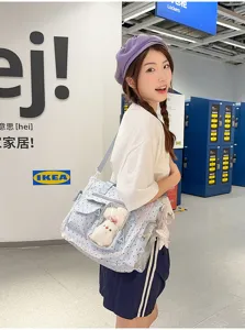 Une femme porte un sac bleu à pois, avec panneau en PVC transparent, bordure en dentelle et breloques