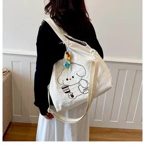 Vue de dos, une femme porte un sac blanc imprimé d’un chien avec café et un charm coloré