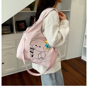 Vue portée d'un sac rose en toile, avec imprimé ours et tasse de café ainsi qu'un petit pendentif