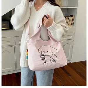 Une personne porte un sac rose illustré d’un chien avec une tasse de café et un petit pendentif.