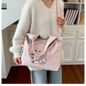 Sac rose à motif d’ours, avec doublure rayée, bandoulière et breloque perlée, porté en scène