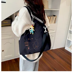 Sac noir porté à l’épaule, brodé d’une tasse et d’un chien, avec un pendentif figurine coloré