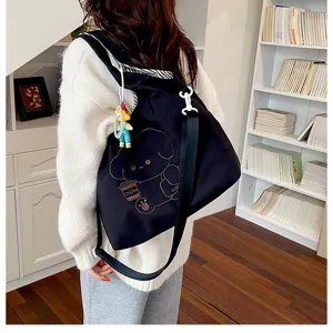 Vue de dos d’un modèle portant un sac noir illustré d’un ours et du mot coffee, avec une breloque