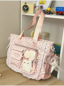 Vue détaillée d'un cabas rose à pois, avec bordure en dentelle, poche transparente et breloque lapin
