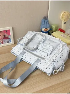Détail d’un sac bleu clair à pois, avec bordure en dentelle, poche transparente, zip et larges anses