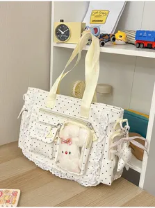 Détail du tissu crème à pois, dentelle, poche transparente et lapin en peluche