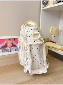 Vue latérale d’un sac blanc à pois, avec dentelle, poche transparente et anses jaune pâle