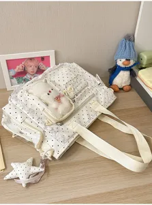 Vue oblique d’un sac blanc à pois, bordure en dentelle, fenêtre PVC et breloque en peluche