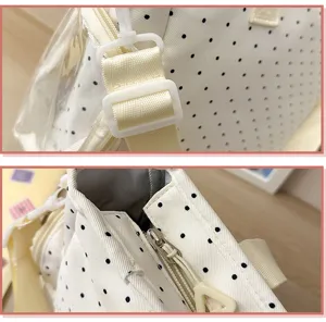 Gros plan sur le tissu à pois noirs, la sangle écrue, la fermeture éclair et la doublure grise