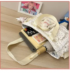 Gros plan d’un sac crème à pois, dentelle, fenêtre transparente et objets sur une table en bois