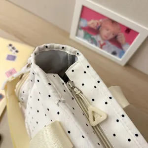 Sac cabas anime ita blanc à pois noirs, avec fermeture zippée et bordure jaune pâle, vu en biais