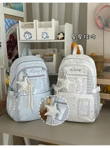 Gros plan sur un pendentif étoile fixé à des sacs à dos bleu clair et blancs à panneaux rayés