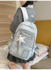 Élève vue de dos avec sac bleu clair à étoiles, rayures, poches zippées et breloque étoile