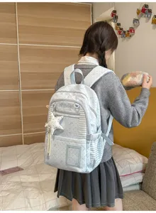 Vue de dos d’une jeune fille portant un sac à dos bleu clair et blanc, à étoiles et rayures
