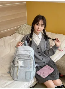 Une élève tient un sac bleu clair à pois, avec rayures, poches zippées et breloque étoile blanche.