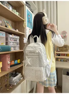 Vue arrière d’une élève portant un sac blanc à étoiles, avec des panneaux rayés et un pendentif.