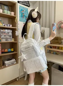 Une élève porte un sac à dos blanc à étoiles et détails rayés, en prenant un selfie au miroir
