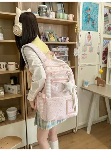 Vue de dos d’une élève portant un sac rose pâle à étoiles, avec des poches zippées à l’avant