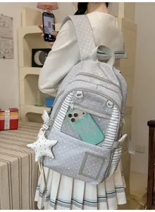 Sac à dos gris à motifs d’étoiles porté en intérieur, avec bordures rayées et pendentif étoile blanc.