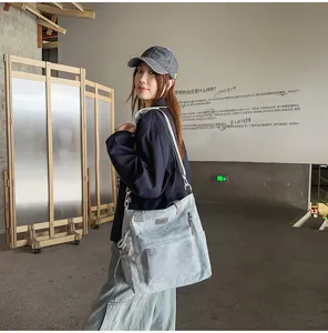Sac bandoulière bleu clair avec étoiles en relief, breloque argentée et zip métallique, porté.