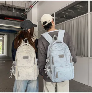 Vue arrière de deux modèles portant des sacs à dos étoilés crème et bleu clair dans un couloir