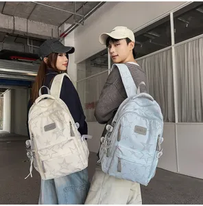 Deux modèles avec des sacs à dos étoilés beige et bleu clair, vus de dos en décor urbain
