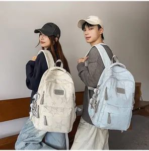 Deux modèles portent des sacs à dos étoilés crème et bleu clair, vus de dos dans un intérieur