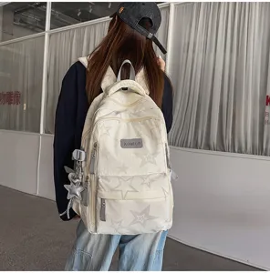 Vue de dos d’une personne portant un sac crème à étoiles claires, avec un pendentif étoile argenté.