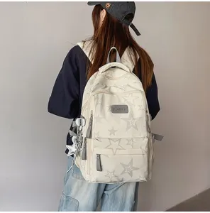 Vue de dos d’un modèle portant un sac crème à motif d’étoiles grises avec un pendentif étoile