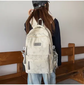 Vue arrière d’un sac à dos crème à étoiles, avec poches zippées et breloque en forme d’étoile.