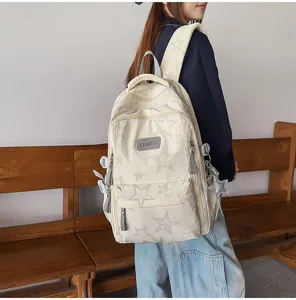 Vue arrière d’une élève portant un sac à dos crème à motifs d’étoiles près d’un banc en bois