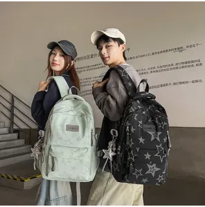 Deux mannequins portent des sacs à dos étoilés, vert menthe et noirs, près d’un escalier.