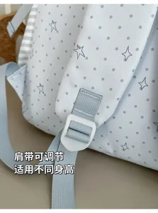 Gros plan sur une bretelle bleu clair réglable, boucle blanche et imprimé gris d’étoiles et pois